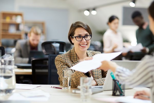 smiling-businesswoman-giving-documents-to-YLNUKBJ.jpg